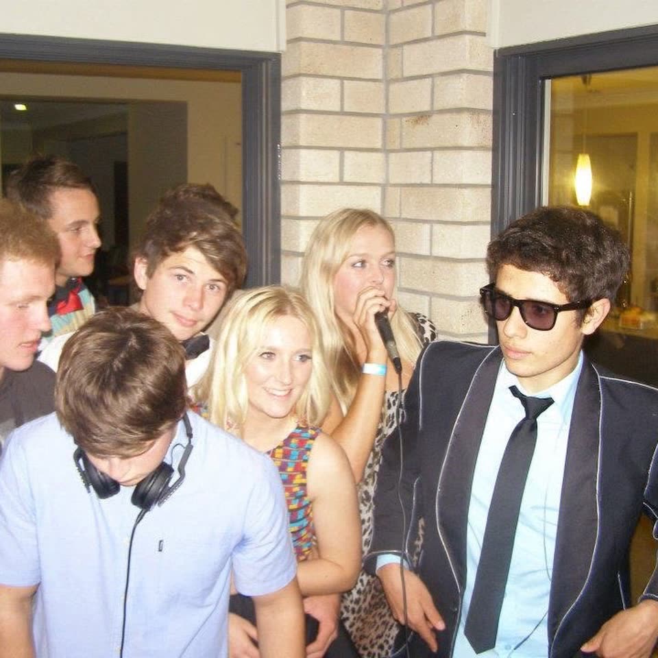 A teenage Harry Hope in a suit and sunglasses MCing a crowded house party