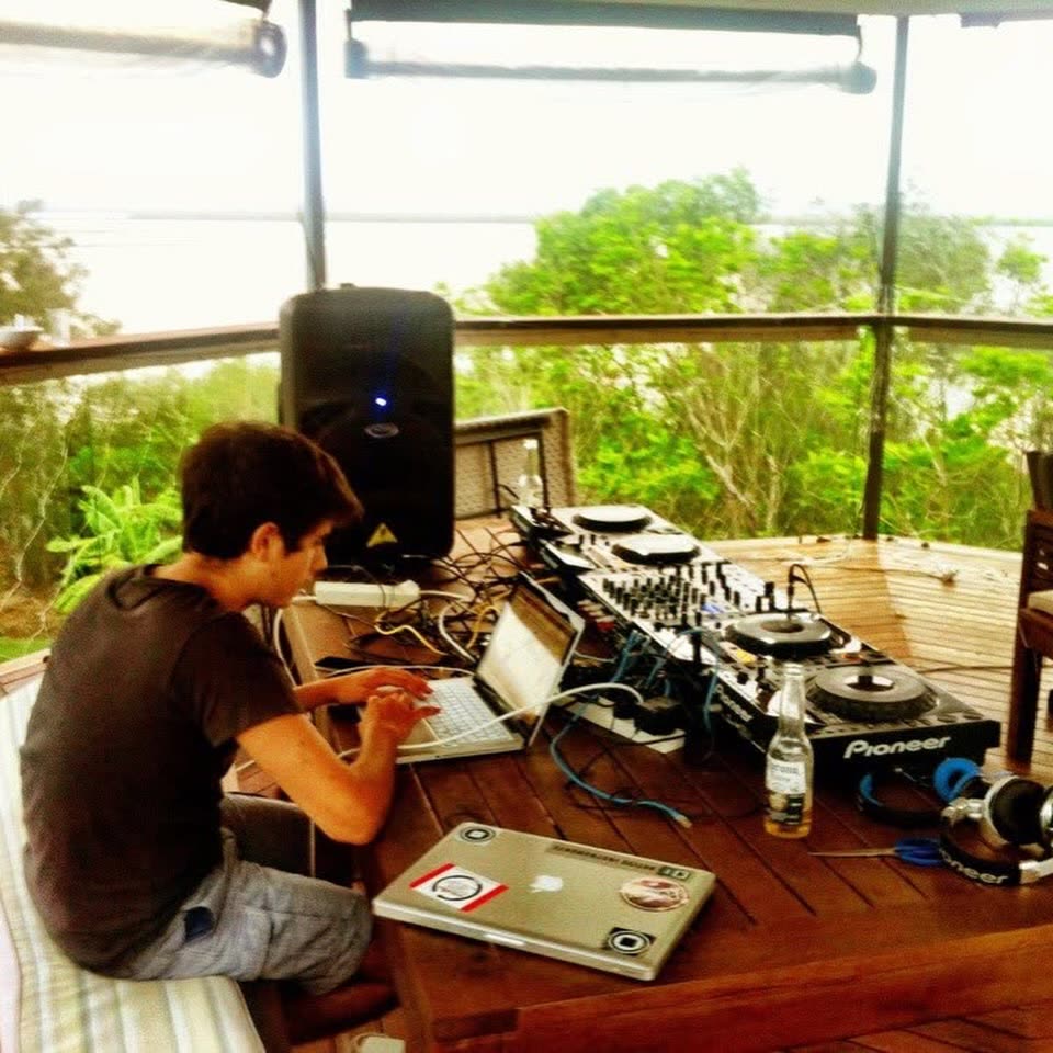 A young Harry Hope hunched over a laptop and Pioneer decks on a wooden deck