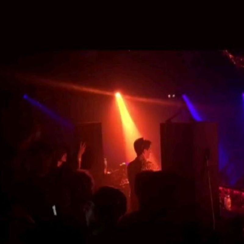 Silhouette behind the decks under an orange beam at a packed LA club
